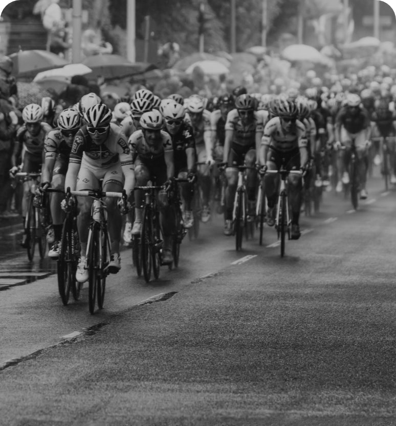 Cyclists racing in a group on a wet road during a rainy day.